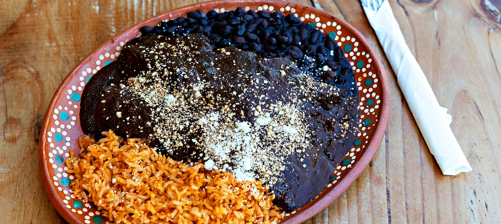 Plato de mole negro con arroz y frijoles en barro oaxaqueño